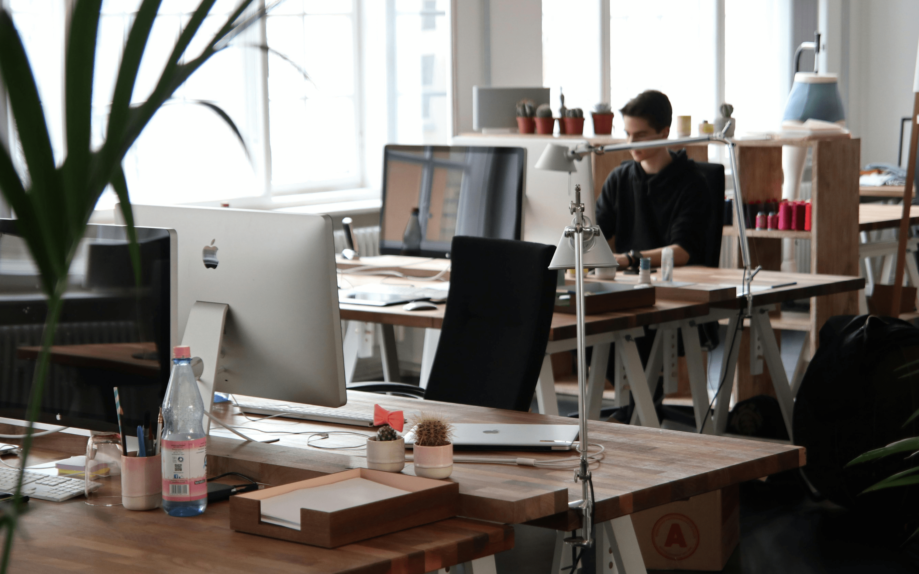 office space full of computers with man working in background
