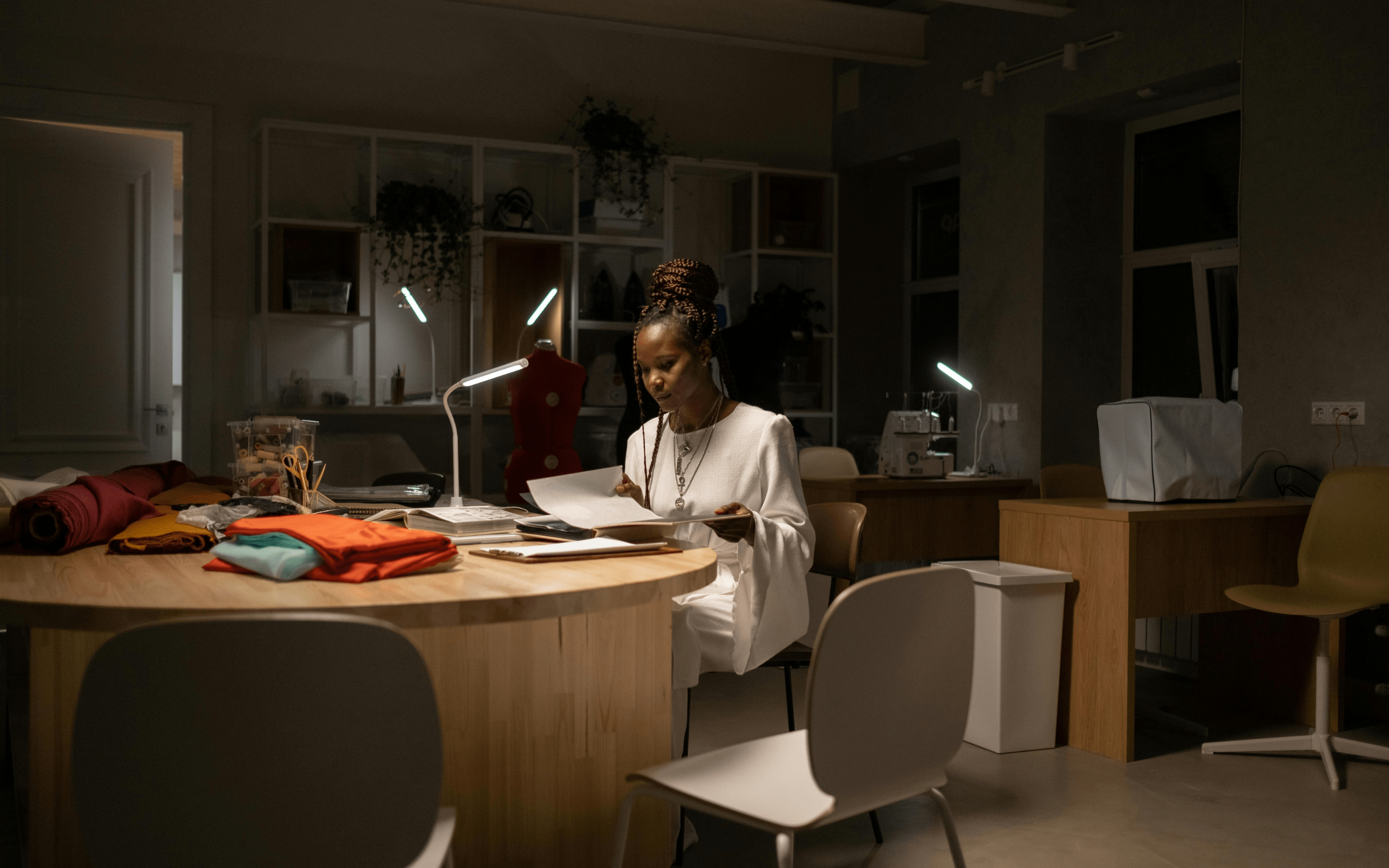 woman working in a dark room reading papers by lamp
