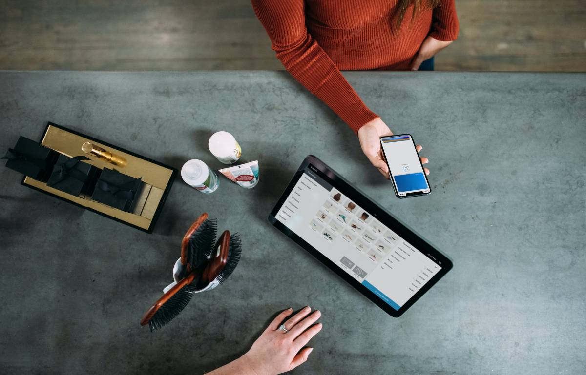 top down shot of two people using tablets and mobile phones to shop online