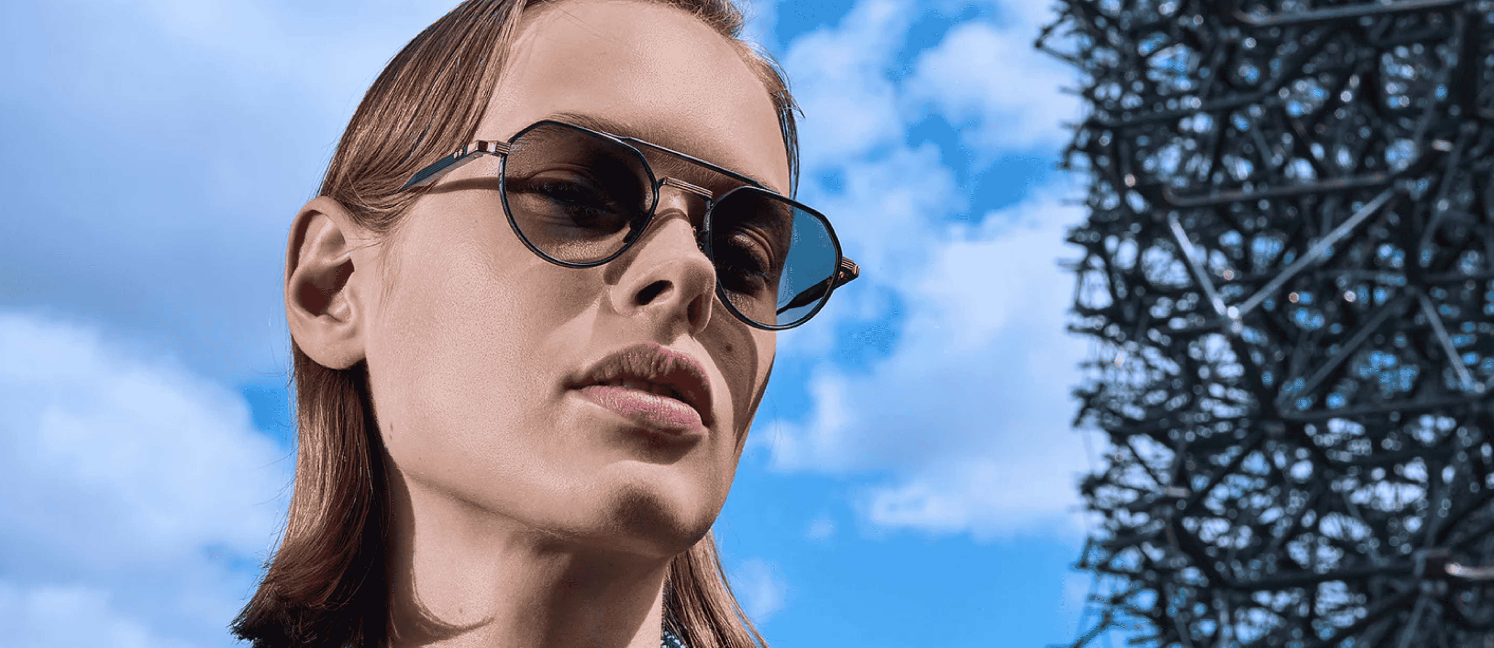 A person wearing Cutler and Gross sunglasses with blue skies